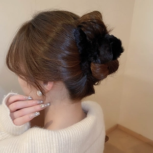 Close-up of a black plush hair claw clip worn on brown hair with a cozy knit sweater