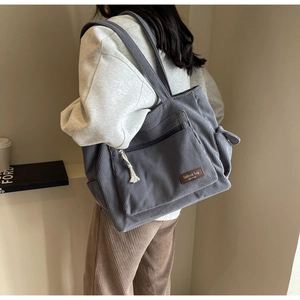Blue-grey corduroy tote bag shown on a model for a casual daily commute look