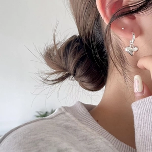 Close-up of minimalist S925 sterling silver hoop earrings with a polished heart charm