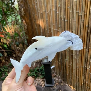 Macro view of a white hammerhead shark hair claw clip held in hand with translucent finish