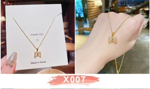Dettaglio macro della collana in titanio dorato con pendente a farfalla e cristalli