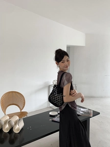 Detail view of a black hollow mesh knit shoulder bag styled with a minimalist outfit