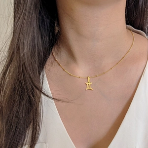 Detailed view of elegant golden Gemini zodiac pendant necklace on a stainless steel chain