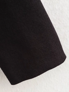 Nahaufnahme des schwarzen Strickstoffs mit Fokus auf Textur und geripptem Bündchen