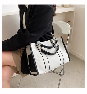 Detail of canvas tote bag with black leather trim and adjustable shoulder strap style