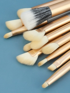 Detailed close-up of 13 professional eye makeup brushes with matte gold handles
