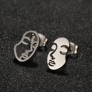 Macro shot of silver abstract face outline earrings with polished metallic finish
