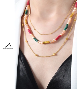 Detail of layered stainless steel necklace featuring pink pearls and colorful tube beads
