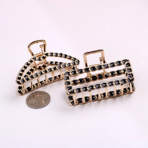 Detail of gold alloy hair claw clips with black chain design and coin for size reference