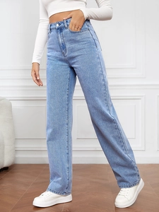 Gros plan d'un jean bleu clair à taille haute et jambe droite avec des baskets blanches