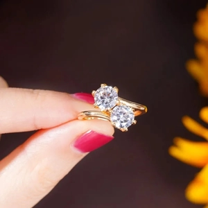 Close-up of gold crossover ring featuring two large round-cut sparkling zircons on hand