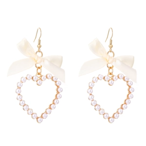 Détail de boucles d'oreilles nœud avec perles d'imitation en forme de cœur doré