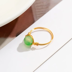 Detail of handmade gold wire-wrapped ring featuring a green translucent bead gemstone