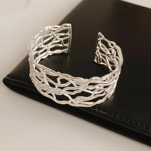 Détail d'un bracelet manchette argenté aux lignes géométriques sur cuir noir