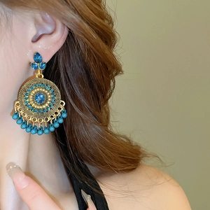 Close-up of bohemian water drop earrings with blue gemstones and metallic mandala detail