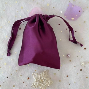 Macro detail of a dark purple satin drawstring gift pouch with elegant silky texture
