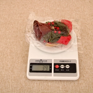 Detail of Christmas iron bell ornament with pine needles and red berries on a scale