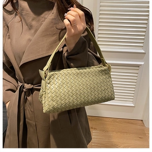 Dettaglio borsa a tracolla intrecciata verde salvia indossata con un trench elegante
