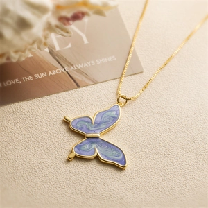 Golden butterfly necklace with purple and blue gradient enamel on a textured background