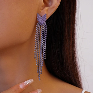 Close-up of elegant purple rhinestone fringe earrings worn by a model in a high-fashion style