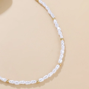 Elegant baroque pearl necklace with gold beads on a soft beige background