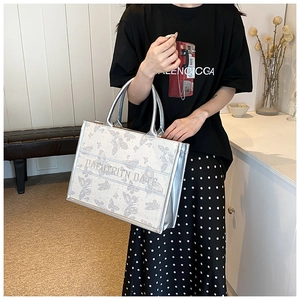 Lifestyle shot of woman holding embroidered butterfly tote bag with silver handles