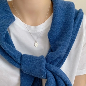 Close-up of minimalist S925 silver necklace with round smile pendant on model sweater