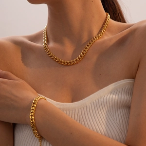 Gros plan sur l'ensemble collier et bracelet gourmette dorés en acier inoxydable