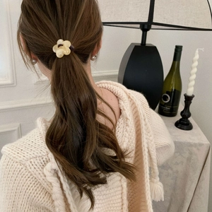 Yellow flower hair tie accessory for women worn on a ponytail with a knit sweater