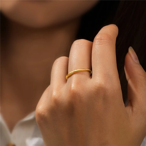 Close-up of minimalist 18K gold ring with a single sparkling zircon on a model hand