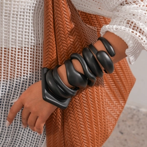 Macro detail of black matte spiral chunky bracelet with unique geometric base on arm