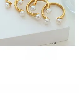 Detail of elegant gold-plated pearl jewelry set featuring minimalist ring and earring designs
