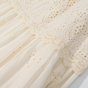 Close-up of delicate lace embroidery and hollow-out detailing on beige shirt fabric