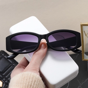Detail of vintage black rectangle sunglasses with purple gradient lenses held by hand