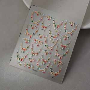 Macro view of 3D Christmas nail decals with colorful rhinestones and festive garland patterns