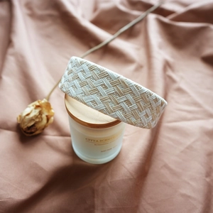 Close-up of woven raffia headband in beige and white on a vintage candle jar