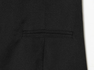 Gros plan sur la poche passepoilée d'une robe courte noire plissée aux coutures nettes
