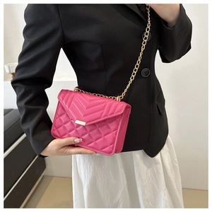 Sac bandoulière matelassé magenta chic avec chaîne dorée sur mannequin élégant