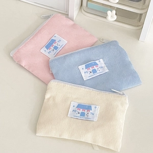 Dettaglio di tre portamonete in velluto a coste rosa, azzurro e beige con cerniera