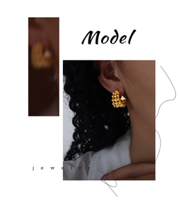 Detail showing gold C-shaped hoop earrings with unique textured bubble design on model