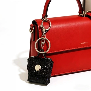 Sparkling black sequin mini bag keychain with silver chain on red leather bag
