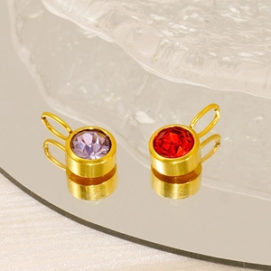 Detail of gold pendants with purple and red birthstones on a reflective mirror surface