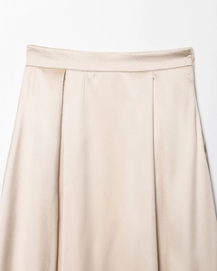 Gros plan détaillé de la jupe en satin champagne avec plis fixes et texture soyeuse