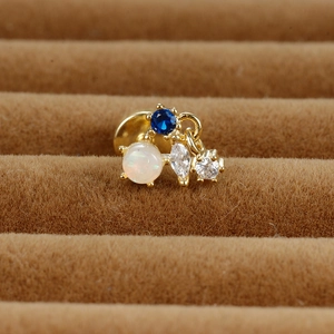 Vue macro d'une puce d'oreille dorée avec saphir bleu, opale et zircon sur velours