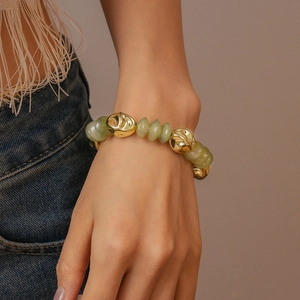 Detail of light green acrylic beads and irregular golden charms on a chic wrist bracelet