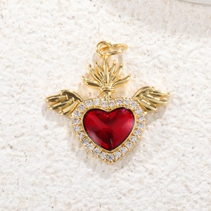 Macro shot of gold-plated red heart pendant with crystal wings on white stone