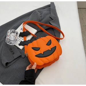 Detail of pumpkin crossbody bag with black bat accents on a stylish blazer background
