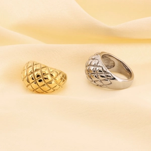 Detailed view of quilted pattern rings in gold and silver finish on yellow fabric