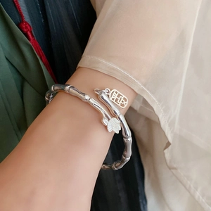 Detail of silver bamboo style bracelet with lotus pendant and Fu charm on wrist