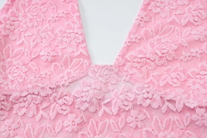 Détail du tissu en dentelle rose montrant les broderies florales et la texture fine